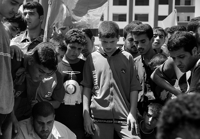 Youth in Gaza City peering into the just-lowered coffin of a 10-year old killed by an errant Israeli missile  strike on a car during Operation Summer Rain (2006).  Photo by Gary Fields